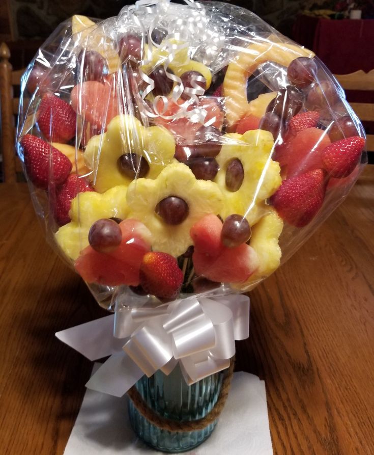 a vase filled with fruit and candy on top of a wooden table