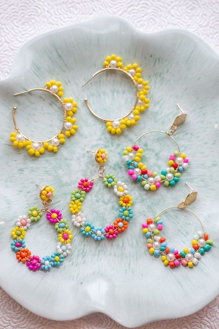 four pairs of beaded hoop earrings on a plate with pink, yellow and blue beads