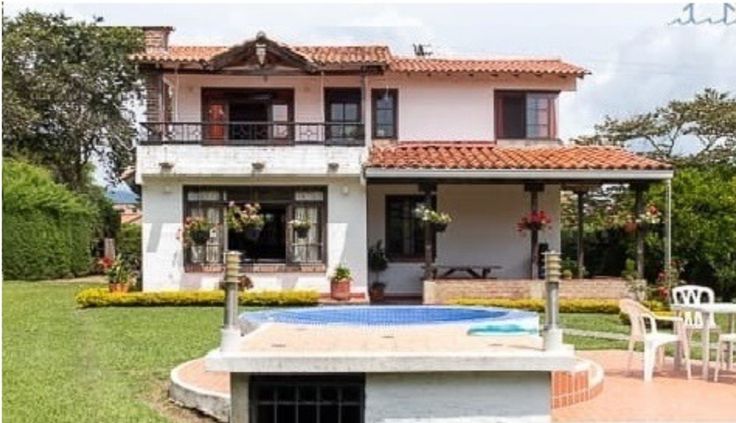 a large white house with a pool in the front yard and patio furniture around it