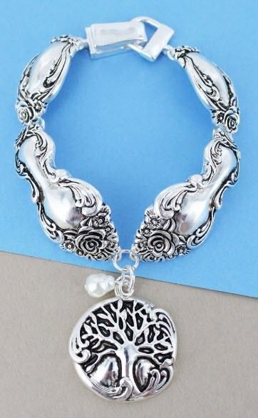 a silver bracelet with a tree charm on it's side and a blue background