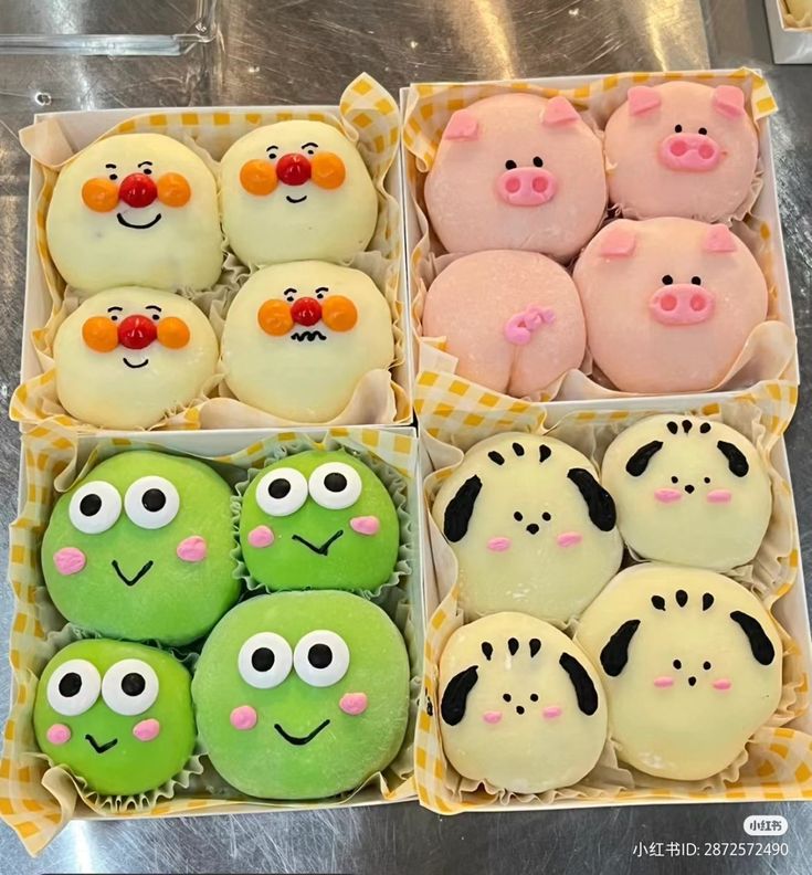 four boxes filled with different types of decorated cakes and pastries in the shape of animals