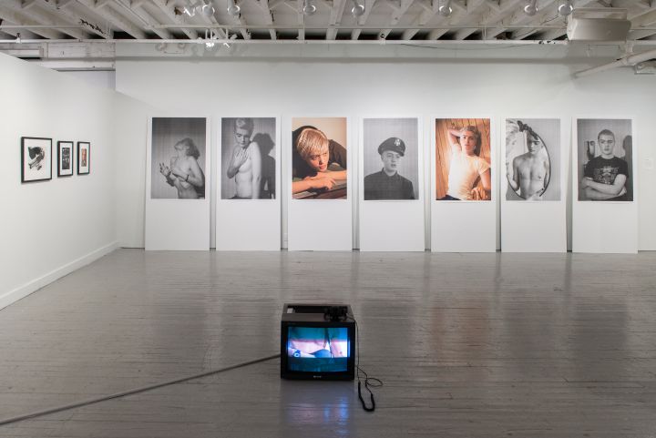 an art gallery with multiple black and white photographs on the wall, including a small television