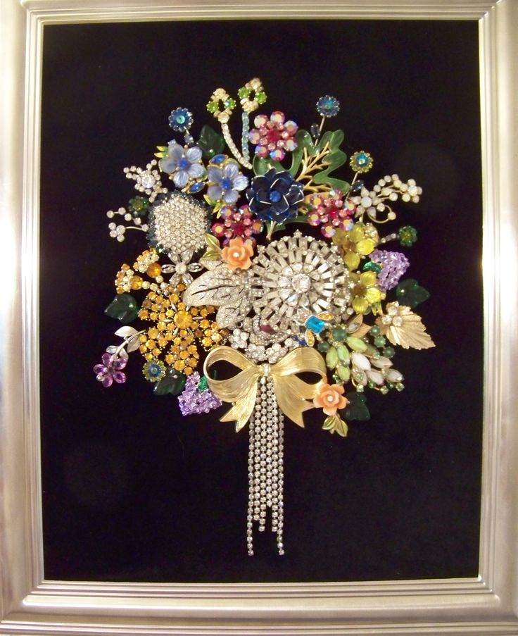 a bouquet of flowers in a silver frame on a black background with pearls and bows