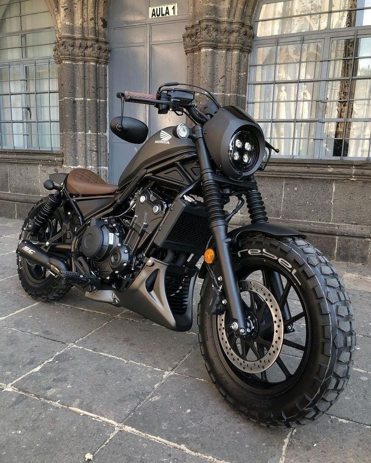 a black motorcycle parked in front of a building with arched windows on the side walk