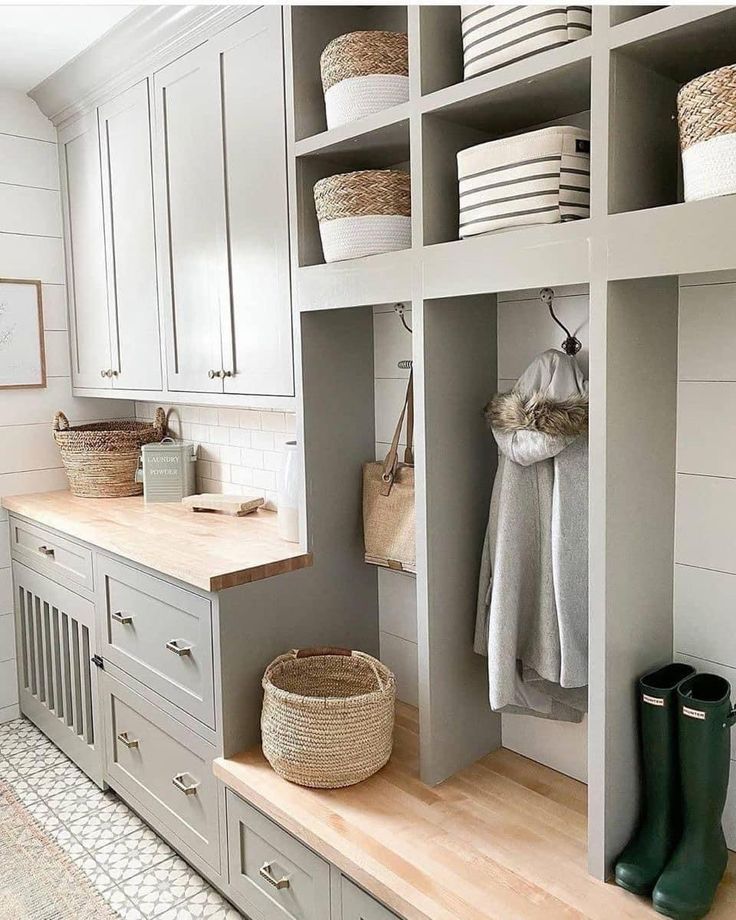 an organized mud room with white cabinets and baskets