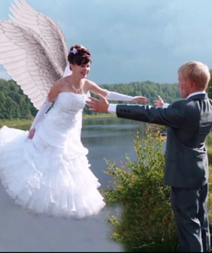 a man and woman dressed in wedding attire standing next to each other near a lake