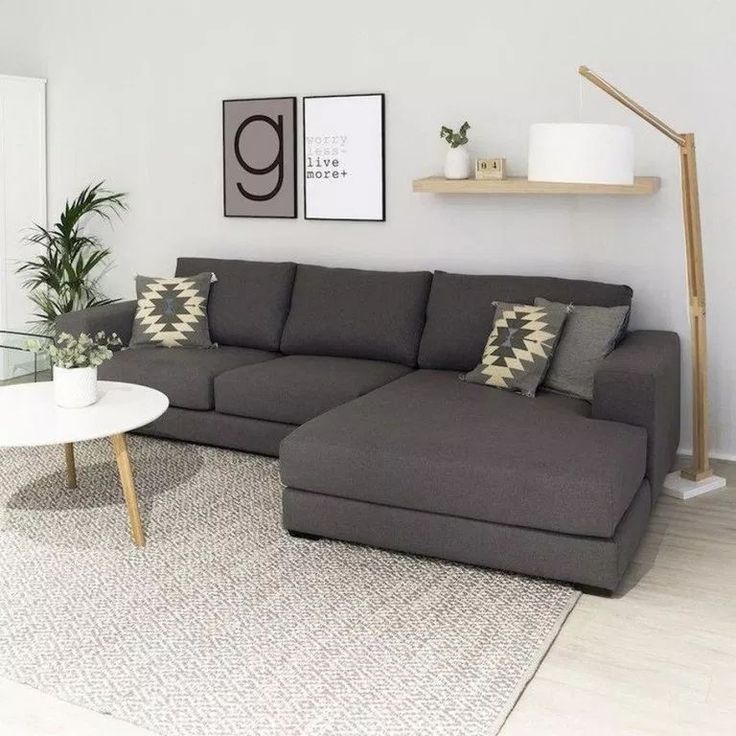 a living room with a gray couch and white table in front of two pictures on the wall