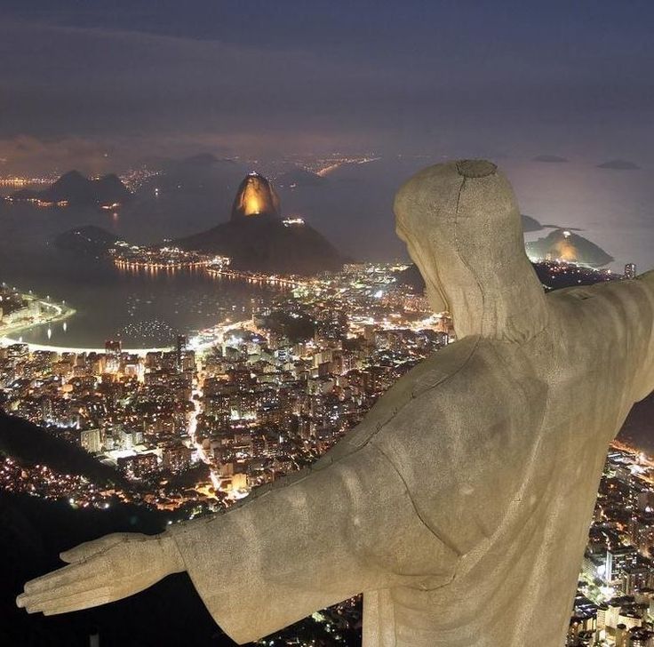 a statue is overlooking the city lights at night