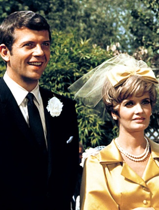 a man and woman standing next to each other in front of some trees wearing formal attire