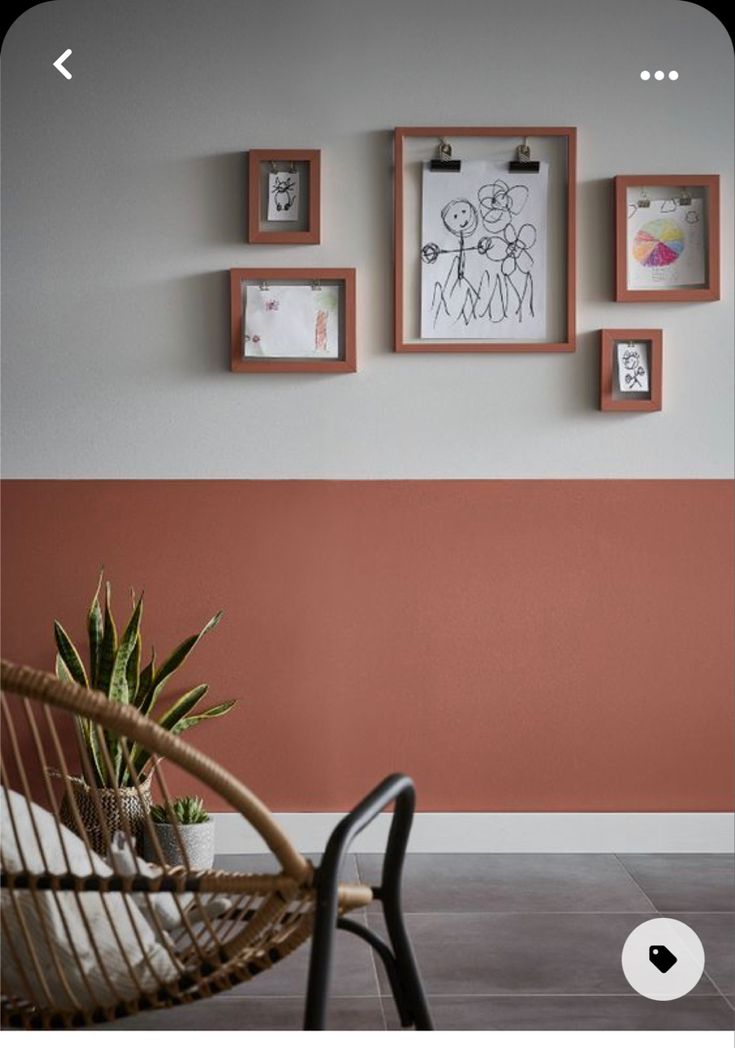 a chair and some pictures on the wall in a room with tile flooring that looks like it has been painted red