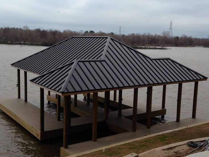 a boat dock with a metal roof on the water