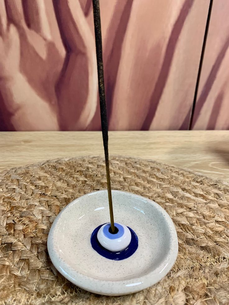 a blue and white bowl with a stick sticking out of it's center on a table