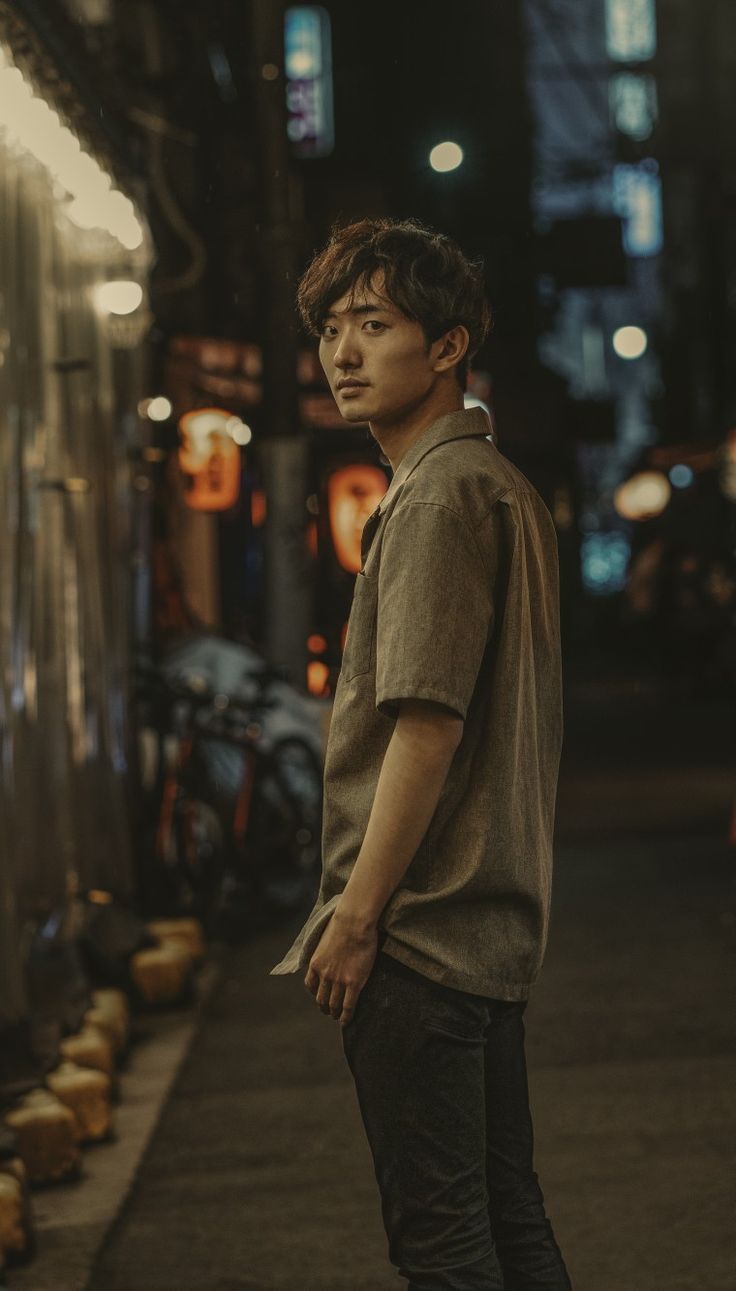 a young man standing on the sidewalk at night