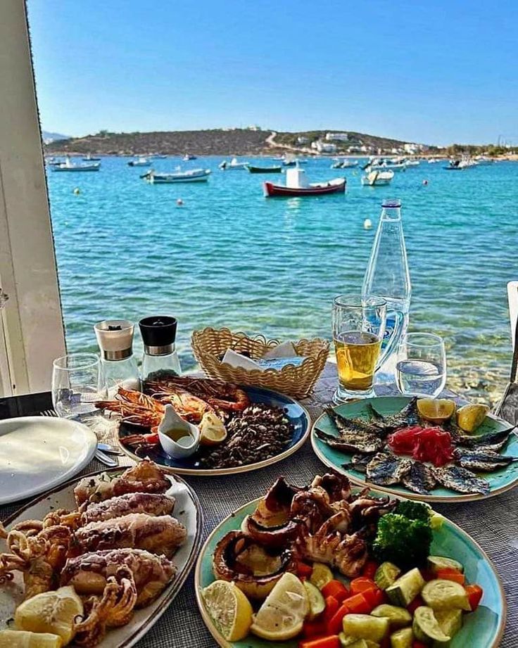 several plates of food sit on a table overlooking the water