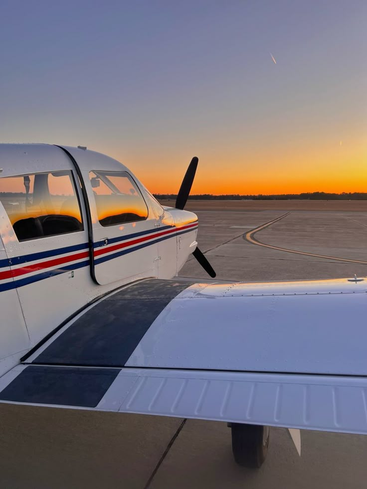 an airplane is sitting on the runway at sunset