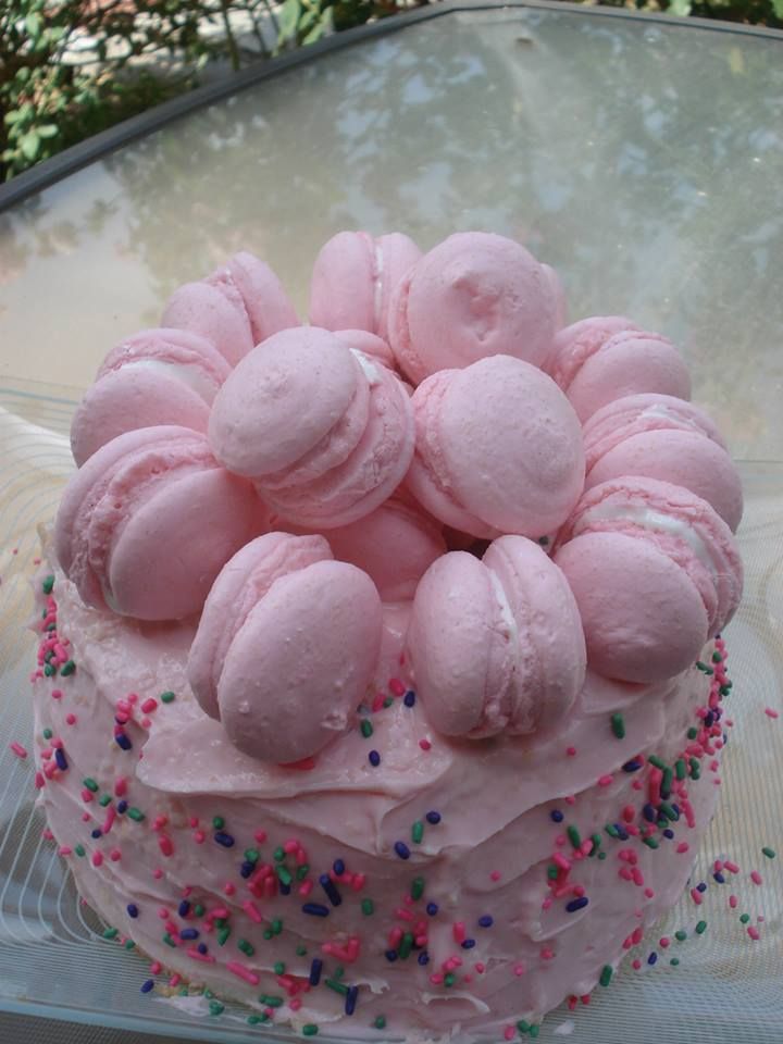 a cake with pink frosting and sprinkles on it sitting on a glass plate