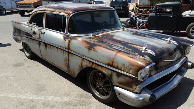 an old rusty car parked in a parking lot