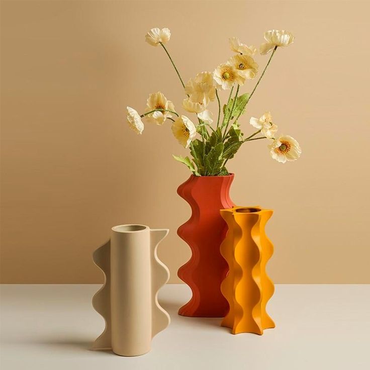 two vases with flowers in them sitting on a table next to each other,