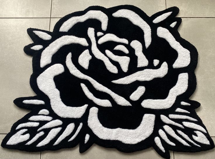 a black and white rose rug sitting on top of a tile floor next to a wall