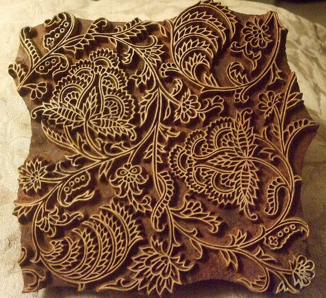 an intricately carved piece of wood sitting on top of a white cloth covered surface