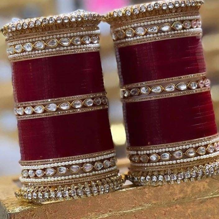 two maroon colored bangles with white stones on them