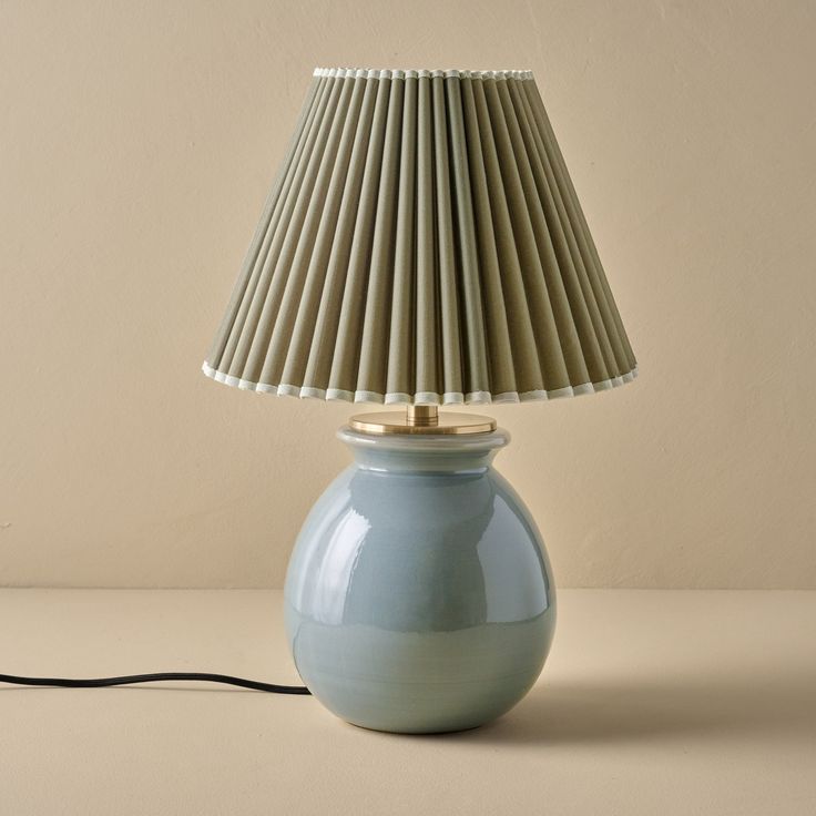 a blue table lamp with a beige shade on it's base and a black cord