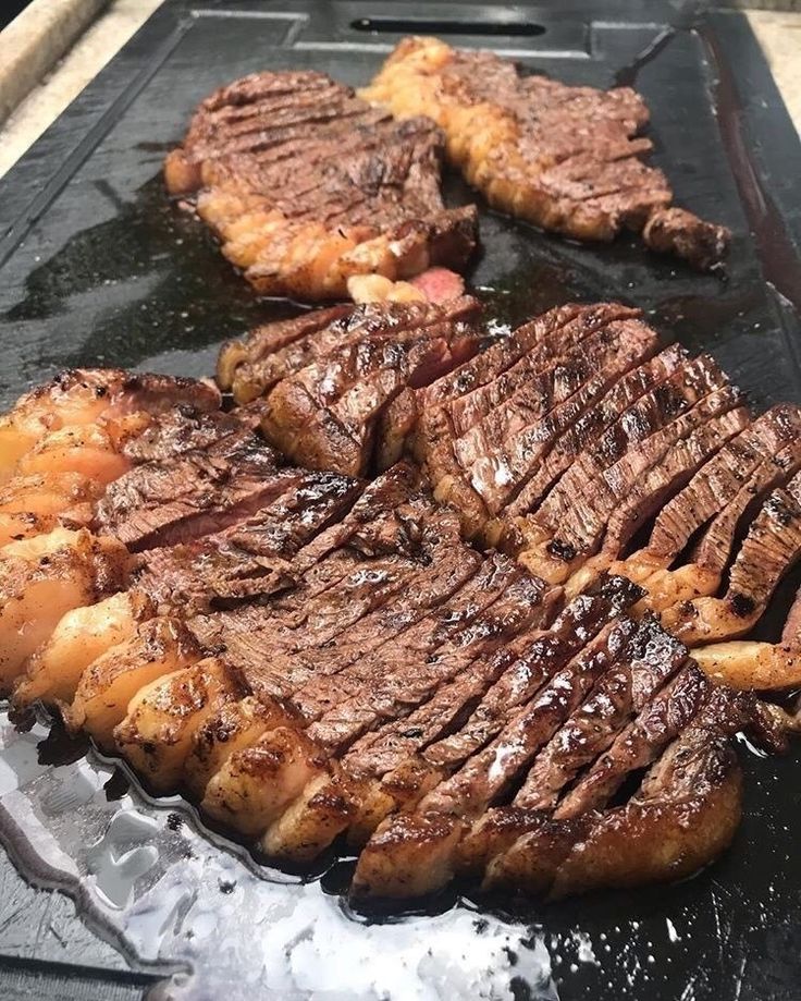 steaks and potatoes are being cooked on the grill