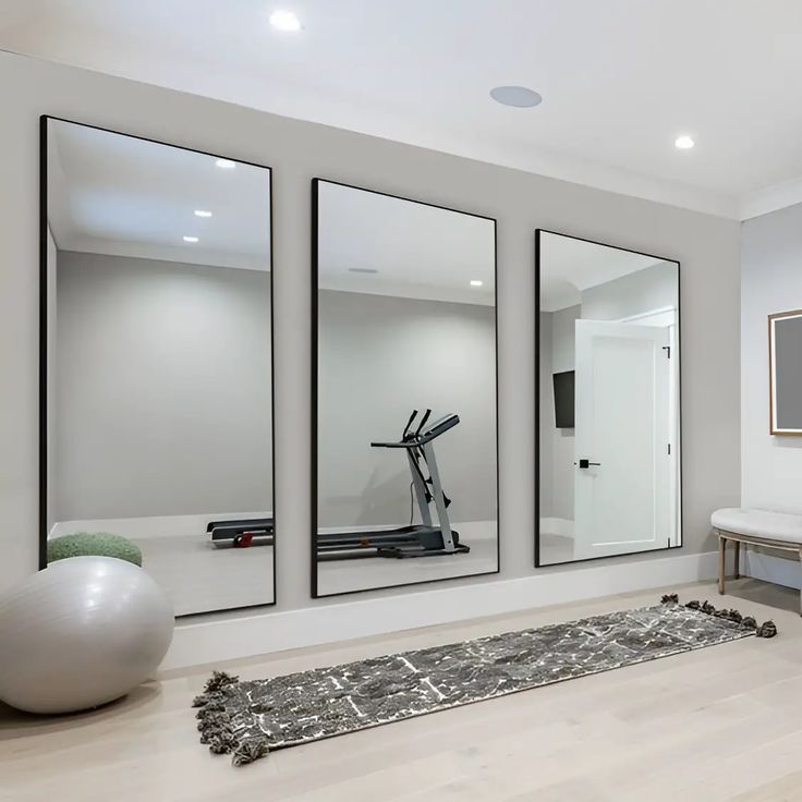 there are mirrors on the wall in this living room with a rug and exercise equipment