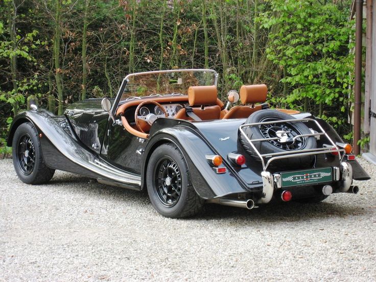 an old fashioned sports car parked in front of a garage