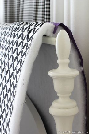 a white bed with a purple and black blanket on it's headboard next to a window