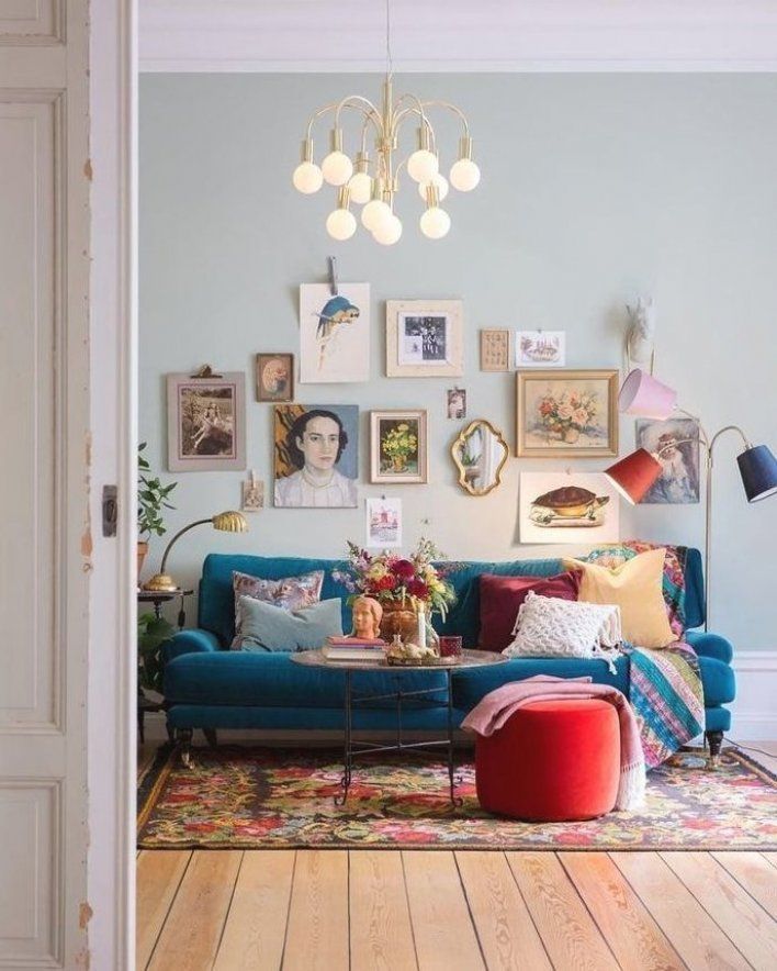 a living room with blue couches and pictures on the wall above them, along with a red ottoman