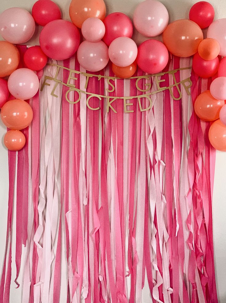 pink and orange balloons are hanging from the wall