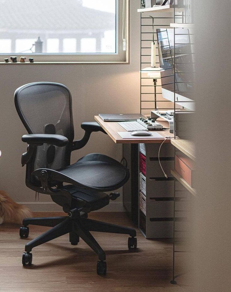 an office chair sitting in front of a window next to a desk with a computer on it