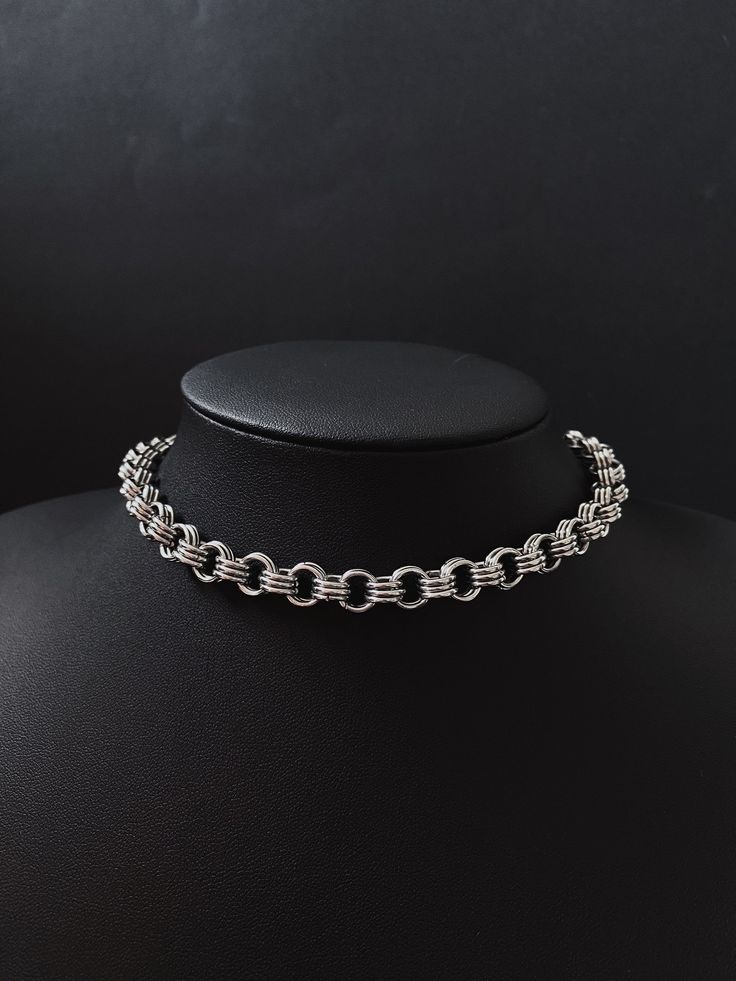 a silver necklace on a black mannequin neck piece, with the chain attached to it