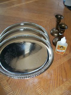 three silver dishes sitting on top of a wooden table next to some bottles and candles