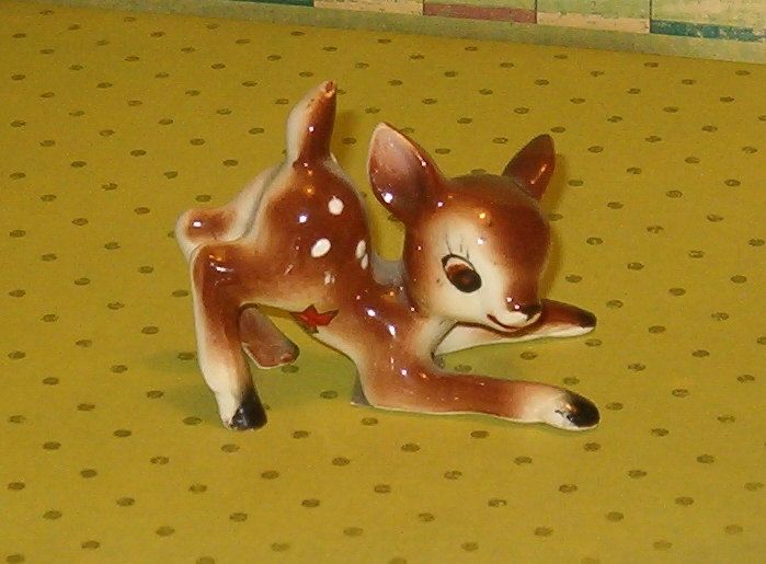 a small deer figurine laying on top of a yellow tablecloth with polka dots