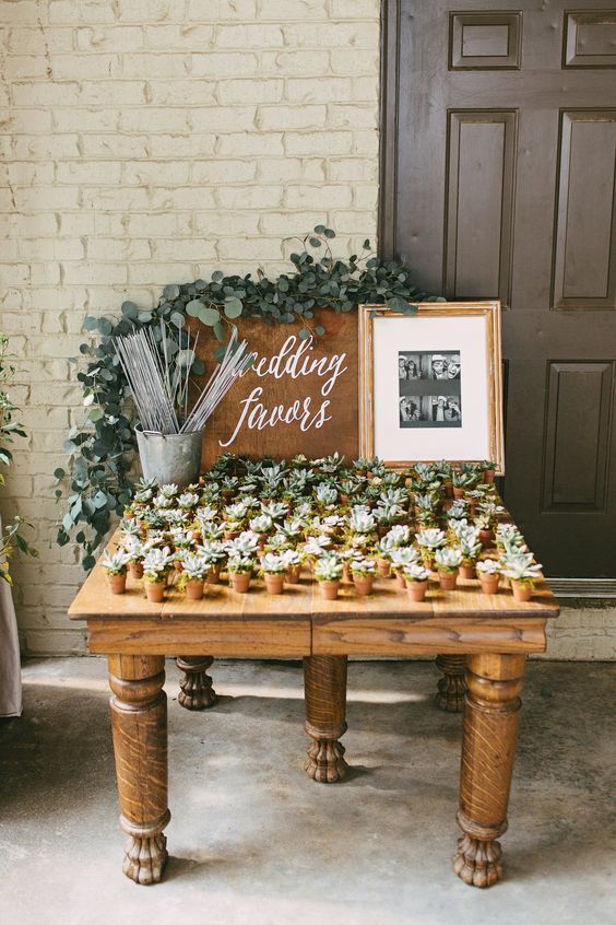 a wooden table topped with lots of cupcakes next to a sign that says wedding favors