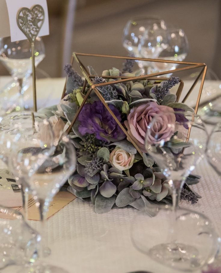 the centerpieces on this table are filled with purple flowers and succulents