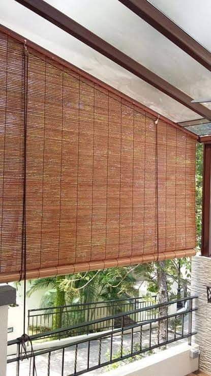 a window covered in bamboo blinds next to a brick wall