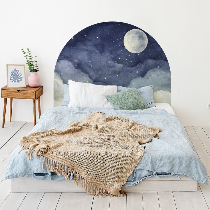 a bedroom with a bed, night sky and stars painted on the wall behind it