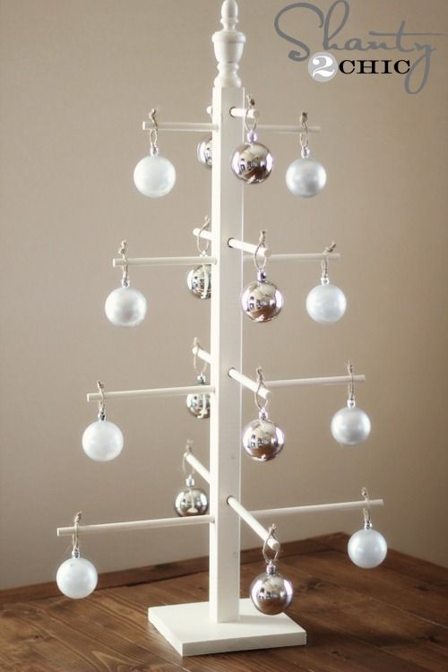 a white christmas tree with ornaments hanging from it's sides on a wooden floor