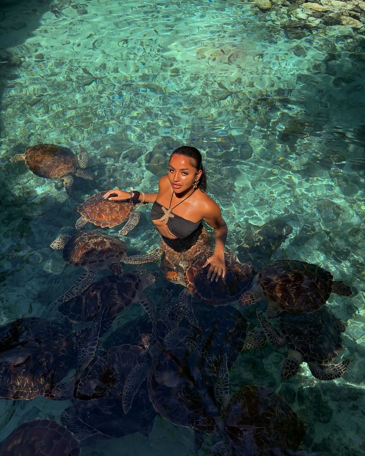 a woman standing in the water with turtles