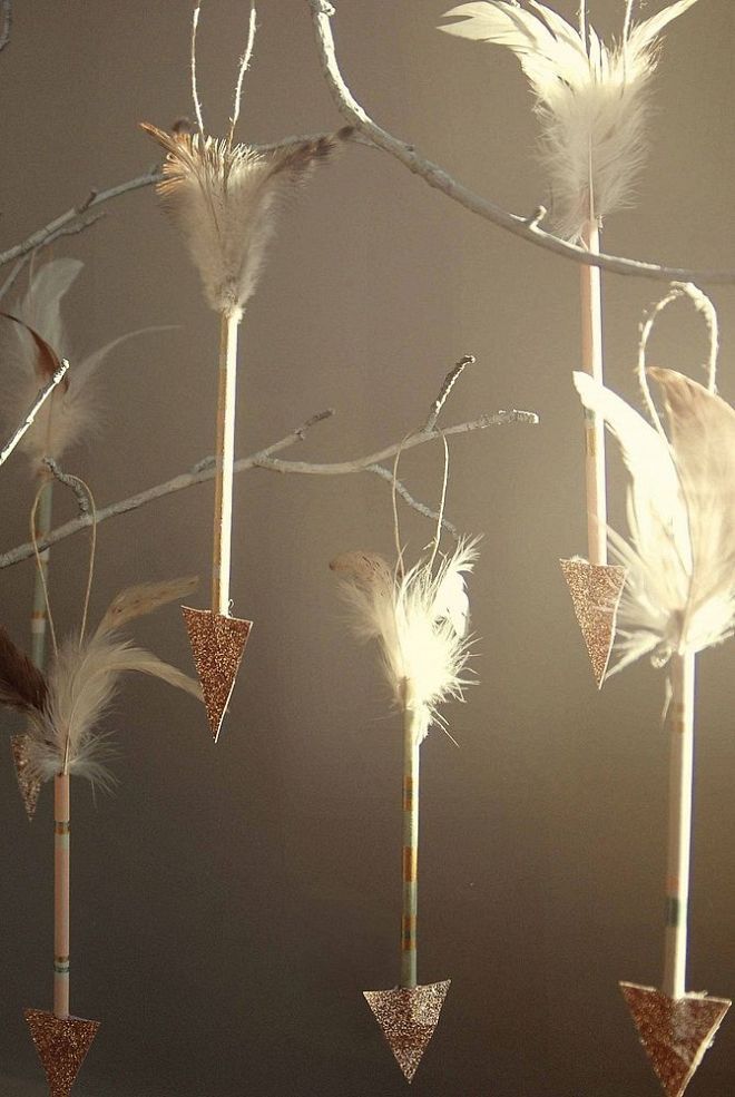 some white feathers are hanging on sticks in the shape of arrows and trees with branches