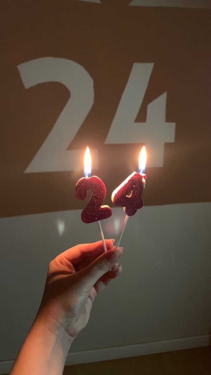 someone holding two candles with the number twenty on them