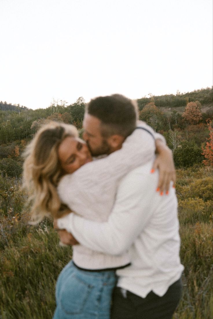 a man and woman hugging each other in a field