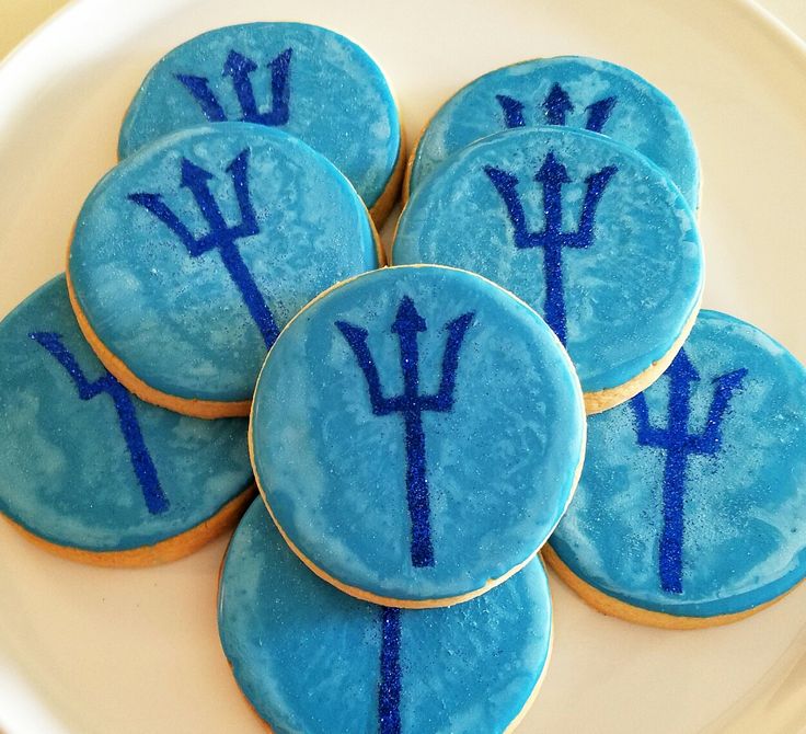 decorated cookies with blue frosting on a white plate, arranged in the shape of zodiac signs