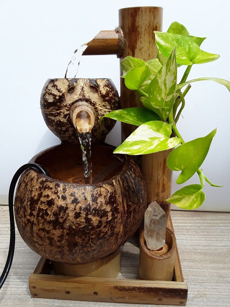 a water fountain made out of wood with a plant in the center and some other items around it