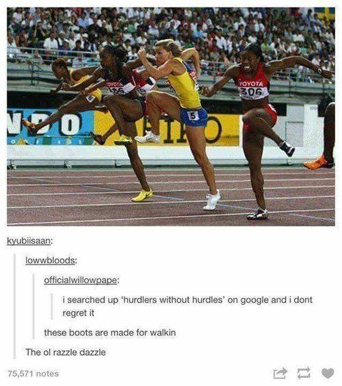 two women running on a track in front of an audience and one is holding her leg up