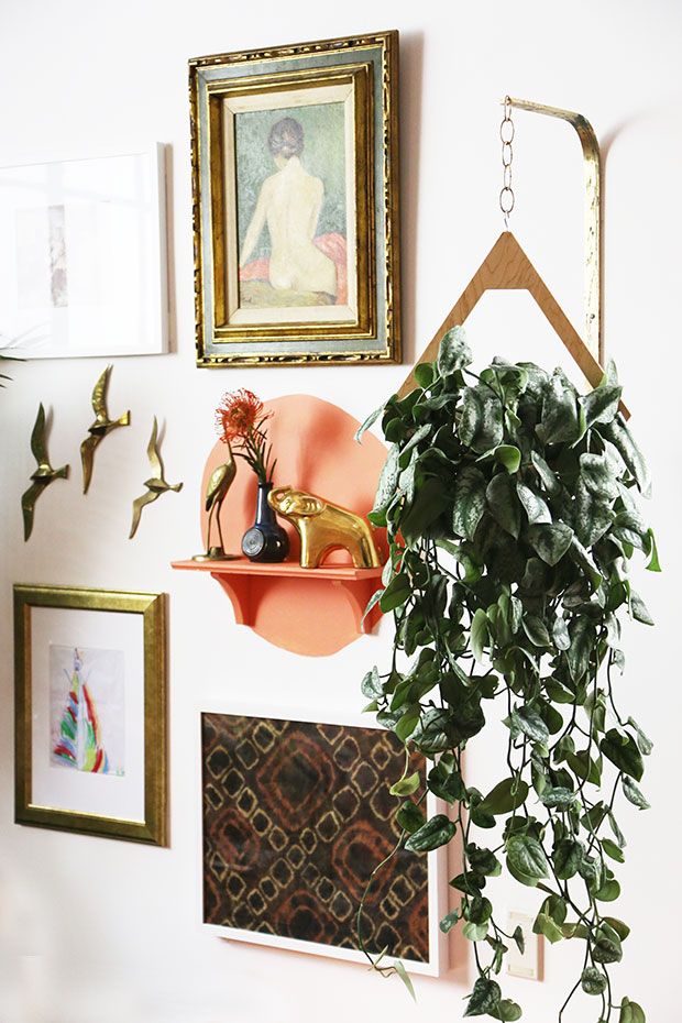 a potted plant sitting on top of a wooden shelf next to pictures and paintings