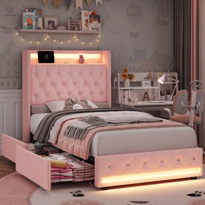 a bedroom with pink furniture and lights on the headboard